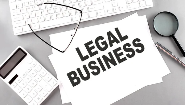 LEGAL BUSINESS text on a paper with keyboard, calculator on grey background