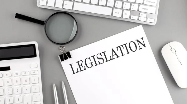 LEGISLATION written on paper with office tools and keyboard on grey background