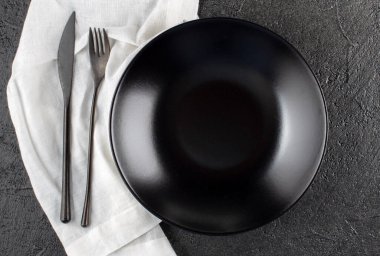 Boş seramik tabak, koyu taş zemin üzerinde keten peçete Boşluk görünümü kopyala