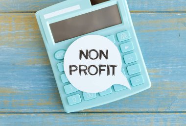 Çıkartmalarda kar amacı gütmeyen metin. Mavi arka planda hesap makinesi. Muhasebe konsepti tot görünümü.