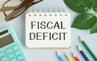 Notlar, hesap makinesi ve beyaz arkaplanda kum saati için FISCAL DEFICIT kağıdı yazılı beyaz kart. İş konsepti. Kahverengi arkaplan.
