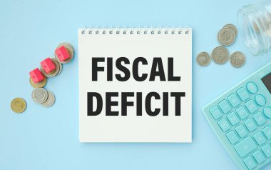FISCAL DEFICIT. KALKULATOR 'un yanındaki beyaz arkaplan üzerine beyaz not defteri kağıdı üzerine metin.