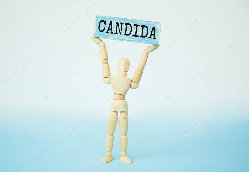 Candida - word from wooden blocks with letters, a parasitic fungus candida concept, blue background