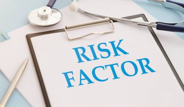 RISK FACTOR. Masaya not defteri, kalem ve steteskop. Tıbbi bilgiler, teşhis..