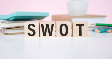 Tahta küplerdeki yazıtlar, beyaz bir defter ve mavi arka planda altın bir kalem.