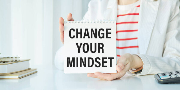 young executive holding card written change your behaviour