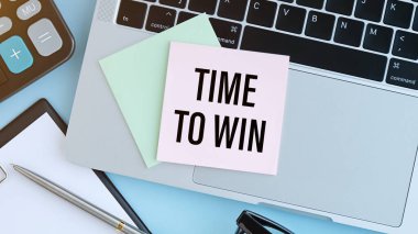Açık mavi arka planda, kahveli beyaz bir kupa, beyaz bir çalar saat, beyaz bir kalem ve Time to WIN yazılı bir defter. Yukarıdan görüntüle