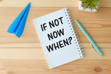 If Not Now, When, text on notepad with pen on wooden background.