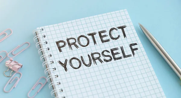 Текст Protect Yourself Блокноті Ручкою Синьому Фоні — стокове фото