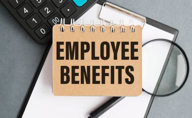 EMPLOYEE BENEFITS metin üzerinde bir fincan kahve ve gri arka planda bardaklar.