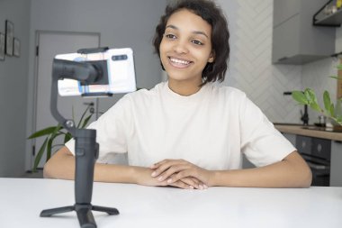 Gülümseyen Afrikalı Amerikalı kadın iş yerinde akıllı telefondan video kaydediyor.