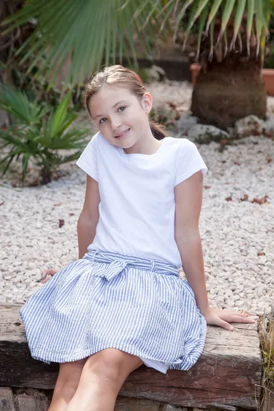 Mutlu kız merdivende oturuyor, gülümsüyor ve kameraya bakıyor.