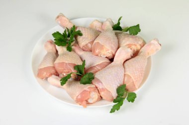 Beyaz bir tabakta çiğ tavuk bacakları, beyaz arka plan