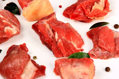 Fresh raw beef meat isolated on white background. Set of raw meat pieces. Meet cubes of raw beef with pepper and green leaves isolated on white background