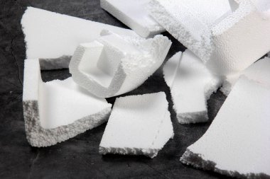 Siyah arka planda farklı şekillerde yapay köpük kağıtlar. Beyaz köpük parçacıkları yaklaşıyor. Parçalanmış köpük parçaları koyu arkaplanda izole edilmiş.