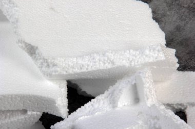 Siyah arka planda farklı şekillerde yapay köpük kağıtlar. Beyaz köpük parçacıkları yaklaşıyor. Parçalanmış köpük parçaları koyu arkaplanda izole edilmiş.