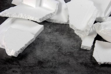 Siyah arka planda farklı şekillerde yapay köpük kağıtlar. Beyaz köpük parçacıkları yaklaşıyor. Parçalanmış köpük parçaları koyu arkaplanda izole edilmiş.