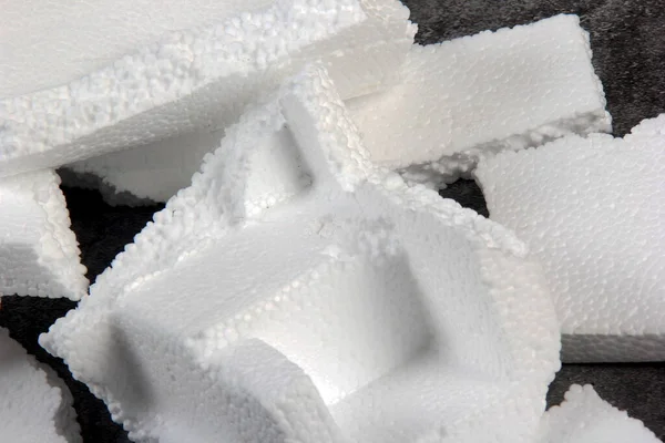 Siyah arka planda farklı şekillerde yapay köpük kağıtlar. Beyaz köpük parçacıkları yaklaşıyor. Parçalanmış köpük parçaları koyu arkaplanda izole edilmiş.