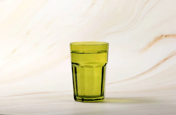Grünes Glas Mit Wasser Und Ein Heller Hintergrund Mit Pflanzenblättern — Stockfoto
