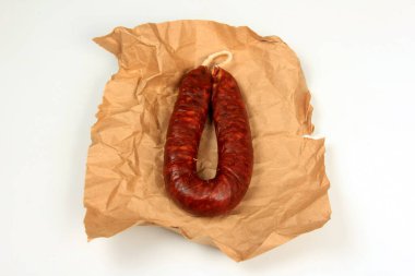 Beyaz arka planda buruşmuş kağıtta İspanyol geleneksel sosisi Chorizo. Taze İspanyol sucuğu.