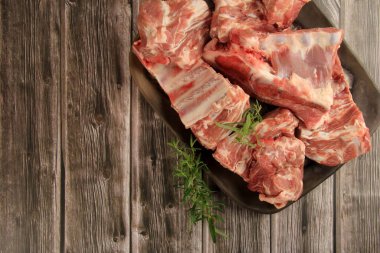 Tabakta taze et parçaları, ahşap arka plan, kemikli taze et.