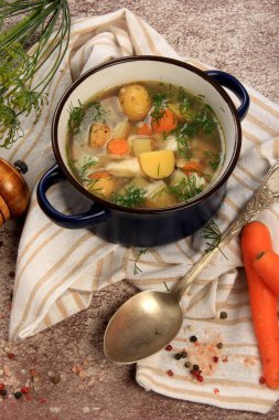 Fresh fish soup with vegetables in bowl on dark background, top view