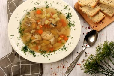 Fresh fish soup with vegetables in bowl on a white board background. Home kitchen recipes