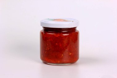 Beyaz arka planda kaynamış kırmızı domates soslu cam kavanoz.