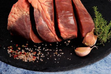 Taştan bir tabakta baharatlı çiğ sığır kalbi. Sığır sakatatı.