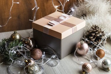 Hediye paketi, Noel süsü ve ahşap bir masada parlayan ışıklardan oluşan bir çelenk. Şenlik konsepti. Noel ve Yeni Yıl Hediyeleri.