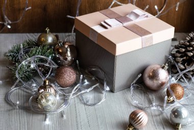 Hediye paketi, Noel süsü ve ahşap bir masada parlayan ışıklardan oluşan bir çelenk. Şenlik konsepti. Noel ve Yeni Yıl Hediyeleri.