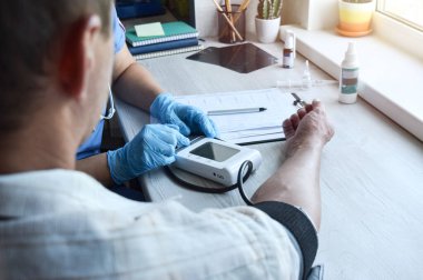 Young girl doctor or pharmacist measures the patient's pressure at home. Provision of medical services at home. Family doctor. Healthcare concept.