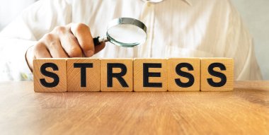 Tahta küplerin dokusuna STRESS yazıtları. Bir iş adamı elinde bir küp tutuyor. Finansal, ticari ya da ekonomik tema üzerine bir yazı.