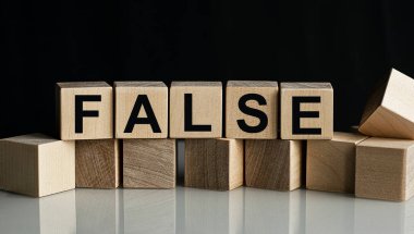 Tahta küplere işyeri ve finans kavramının karanlık bir arka planda izole edilmiş FALSE yazıları.