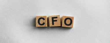 The inscription CFO on wooden cubes on a light background, on the table top view. Graphic resources for promoting the concept of the firm and brand.