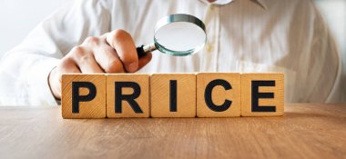Ahşap küplerin dokusunda PRICE yazıları var. Bir iş adamı elinde bir büyüteç tutuyor ve küplerdeki yazıyı inceliyor. Finansal, ticari ya da ekonomik tema üzerine bir yazı.
