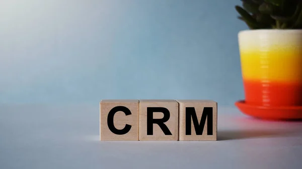 Ahşap küplere işyeri ve finans kavramına ait CRM yazıları mavi bir arkaplanda izole edilmiştir..