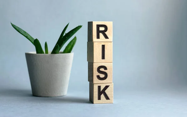 Ahşap küplere işyeri ve finans kavramına ait RISK yazıtları mavi arka planda izole edilmiştir..