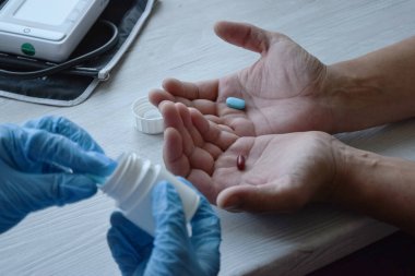 Genç bir doktor ya da eczacı kız hastaya ilaç sunar. Evde tıbbi hizmetler sağlanıyor. Haplar ellerde. Sağlık hizmetleri kavramı.