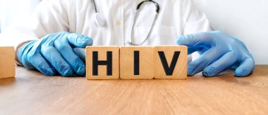 Mavi eldivenli genç bir erkek doktor üzerinde HIV yazan küpleri tutuyor. Sağlık ve Tıp Konsepti.