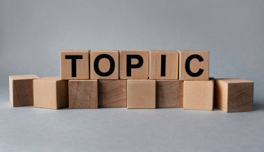 TOPIC, beyaz arkaplandaki tahta küplerin üzerindeki yazı