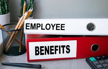 Masaüstünde hesap makinesi ve kalemle birlikte duran kırmızı ve beyaz klasörler. Dosyadaki harflerin finansal ya da pazarlama önemi var. İş konsepti.