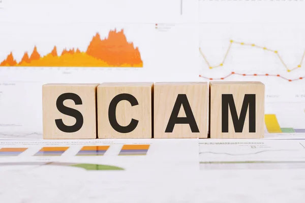 Hafif bir arkaplanda, grafikler, diyagramlar ve SCAM sözcüğüyle ahşap küplerde .