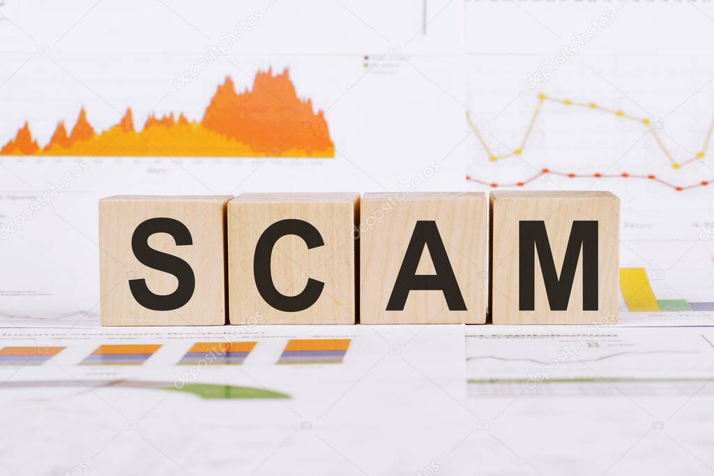 On a light background, graphs, diagrams and wooden cubes with the word SCAM .