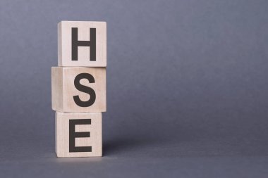 HSE - Sağlık Güvenliği Ortamı, tahta bloklara yazılmış metin, gri arkaplan.