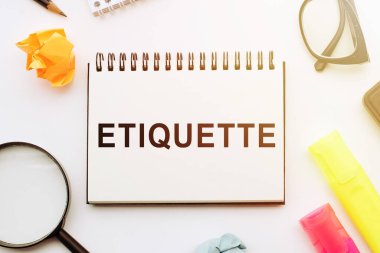 Not defterindeki yazı, ETIQUETTE, gözlüklerin yanında ve beyaz arka planda büyüteç. Bir iş kavramı.