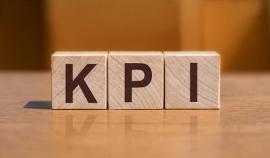 KPI - anahtar performans göstergesi, turuncu duvar arkaplanındaki tahta küpler üzerine metin.