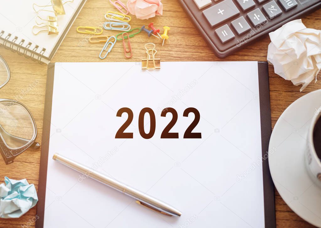 2022 New year text on white paper with calculator ,notepad, glasses, cup of coffee and pen.
