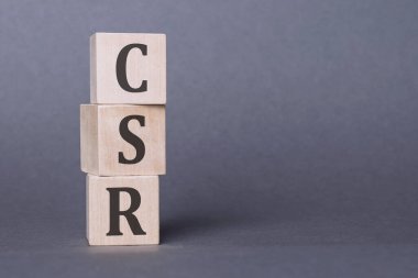 CSR - kurumsal sosyal sorumluluk, tahta bloklara yazılmış yazı, gri arkaplan üzerine.
