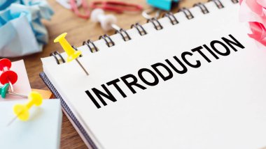 INTRODUCTION - Ahşap zemin üzerinde kırışık kağıt ve kağıt iğneler ile bir not defteri üzerinde metin.